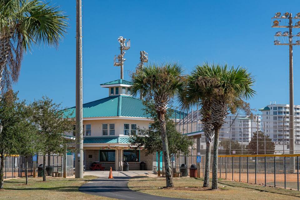 A building with a blue roof and a fenced sports field.