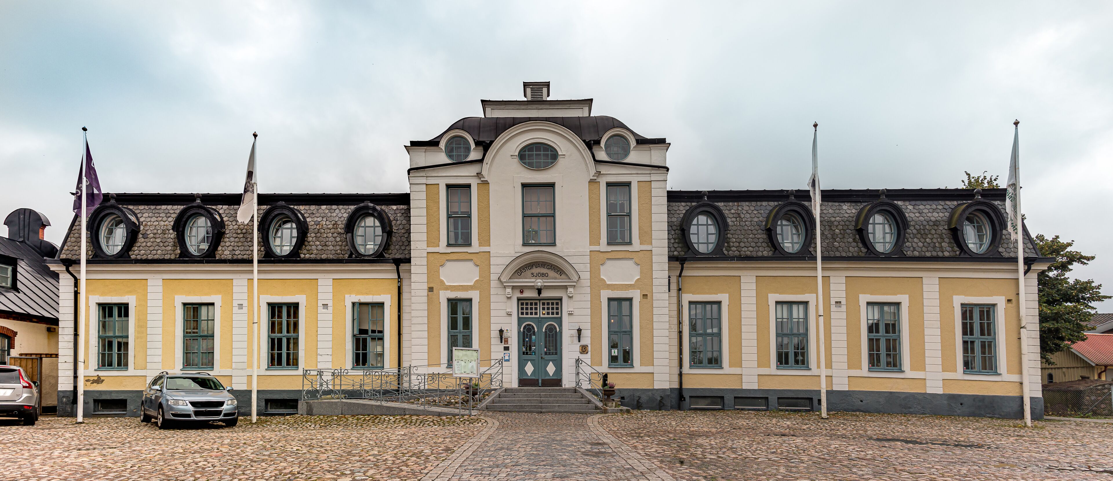 A historic building with a yellow facade, arched windows, and a central entrance.