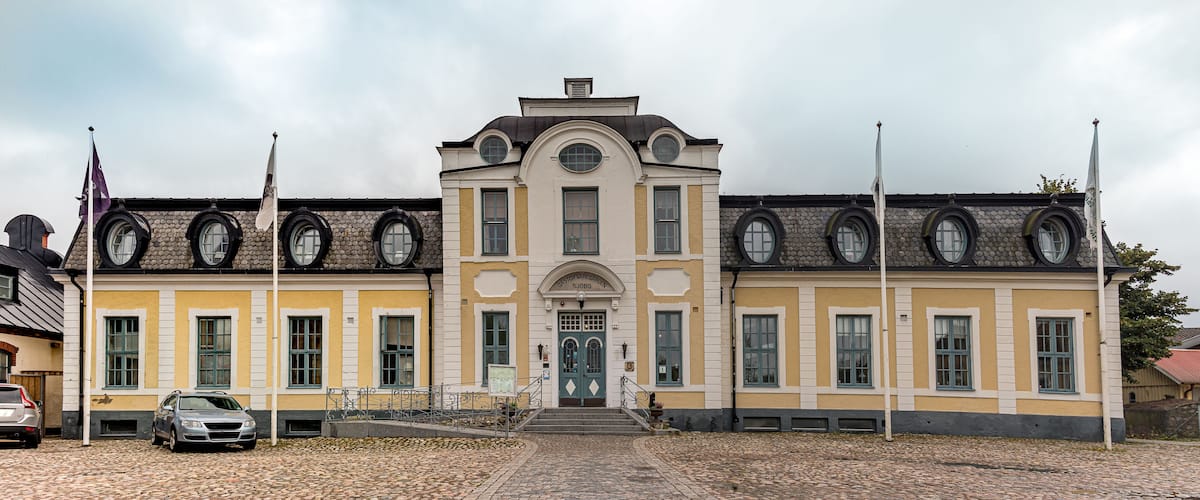 A historic building with a yellow facade, arched windows, and a central entrance.