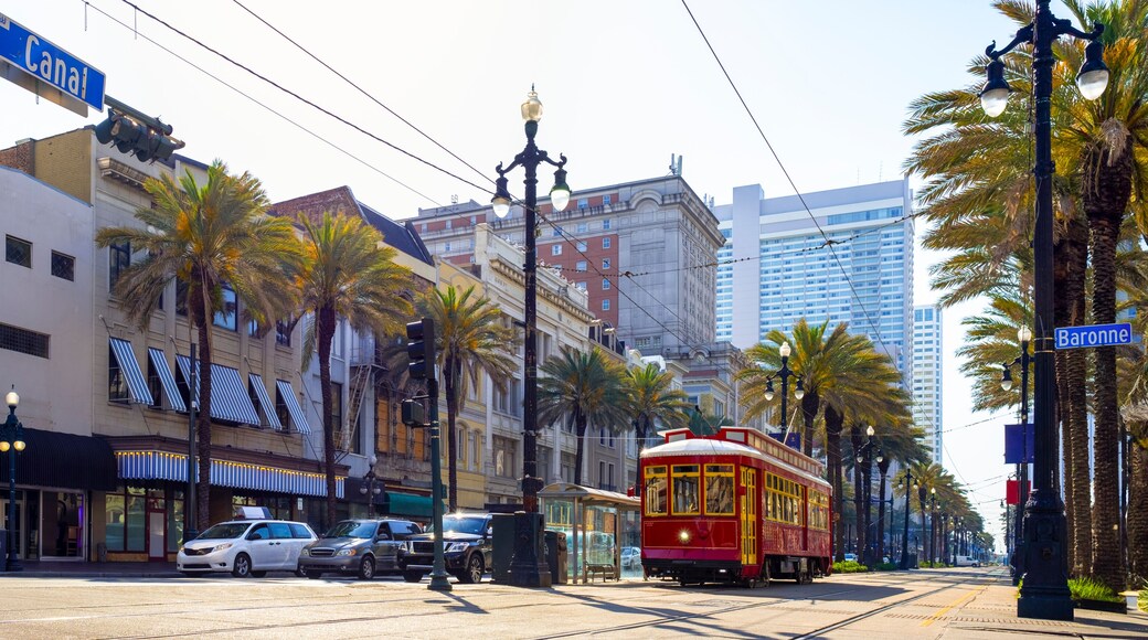 A street with a red trolley, palm trees, and buildings with striped awnings.