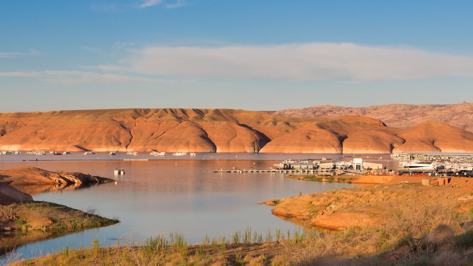 A desert landscape with a large body of water, boats, and a small settlement.