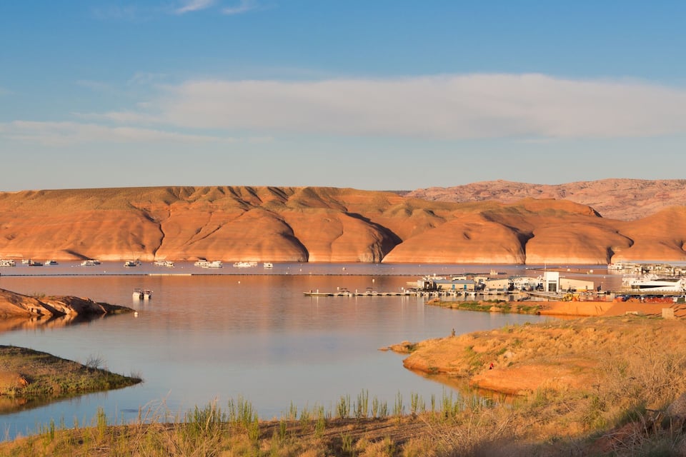 A desert landscape with a large body of water, boats, and a small settlement.