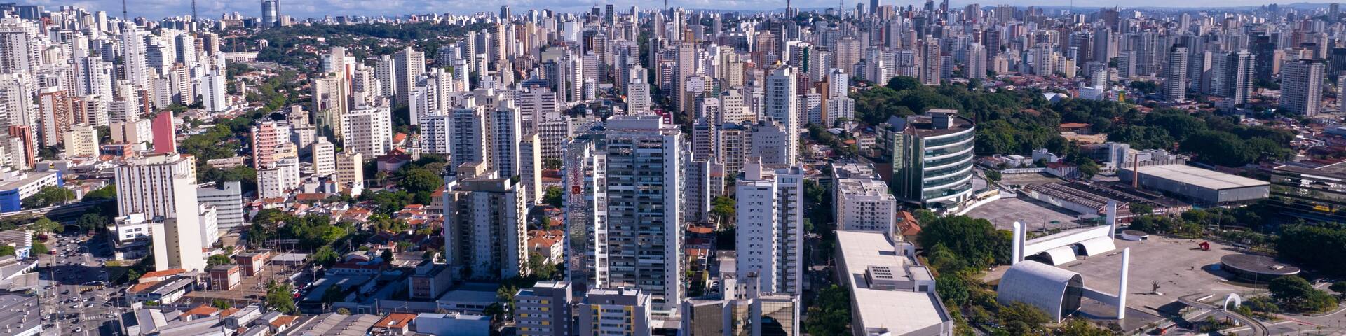 A densely packed urban skyline with high-rise buildings, a large circular structure, and a mix of greenery.