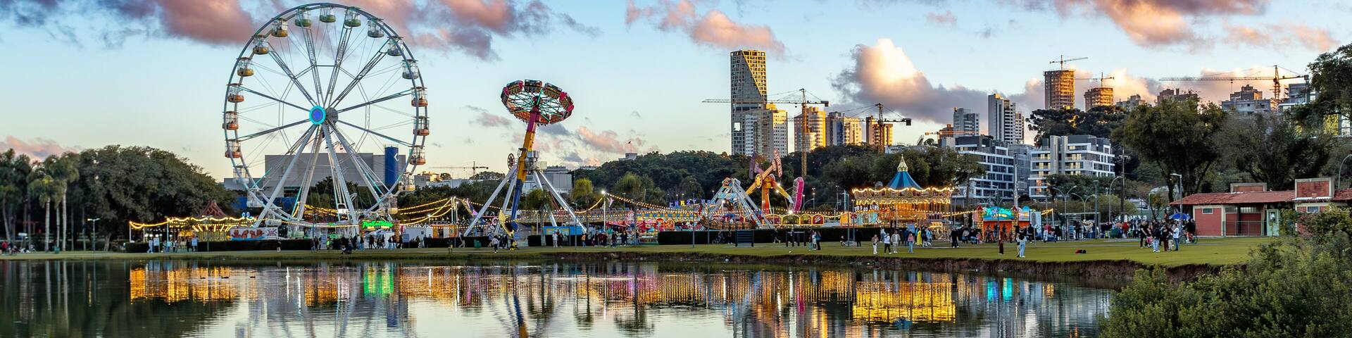 Vibrant Barigui Park in Curitiba, capital and largest city in the state of Parana, featuring a funfair and a ferris wheel against the city skyline. Brazil.