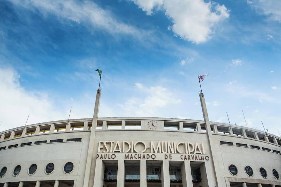 Un estadio con el nombre 'Estadio Municipal Paulo Machado de Carvalho' y dos banderas en los mástiles.