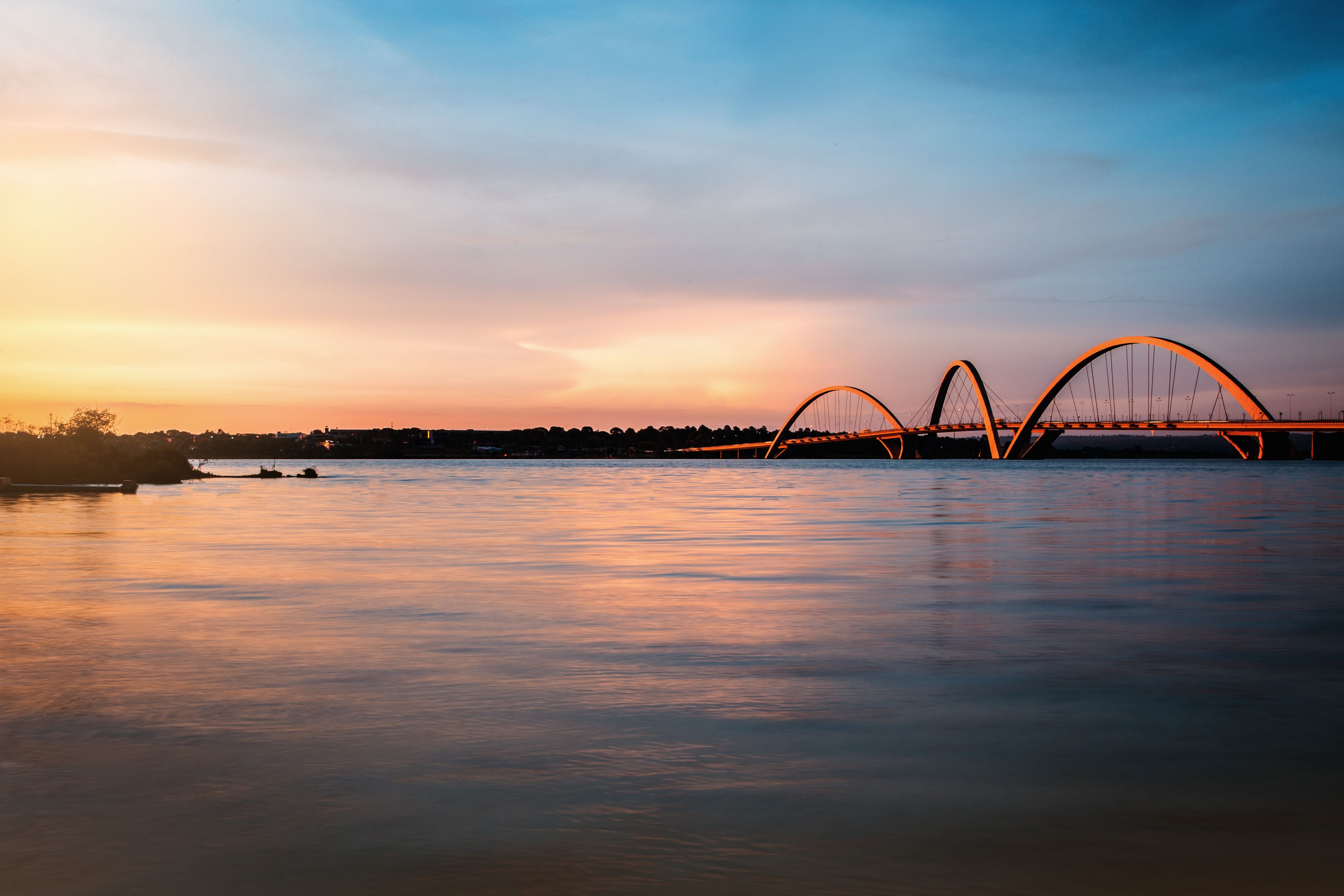 Un puente con dos grandes arcos sobre una masa de agua al atardecer.