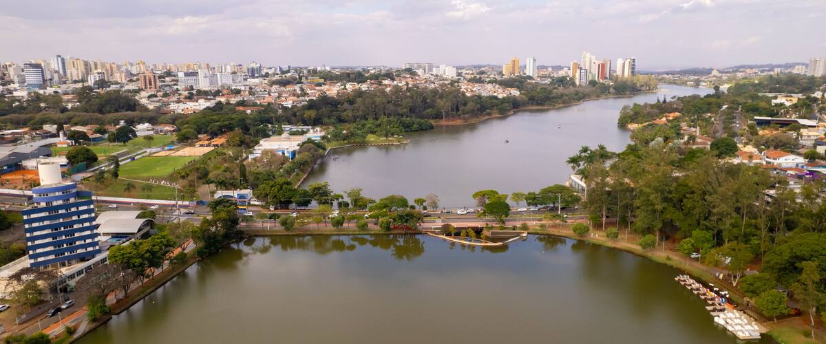 A river winding through a city with buildings, greenery, and a clear sky.