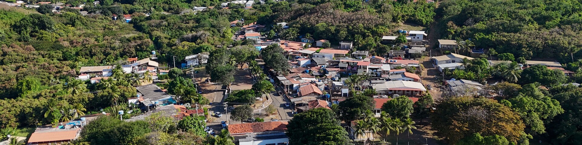 Un pueblo enclavado en un valle, con una colina destacada al fondo.