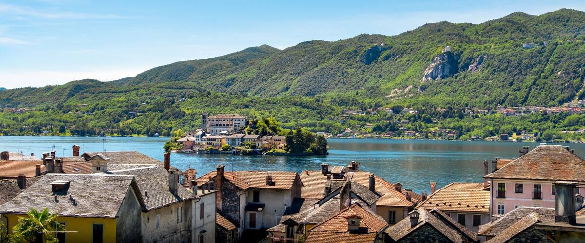 A lake surrounded by mountains and a small island with a building.