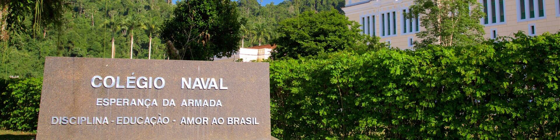 A sign for Colegio Naval Esperança da Armada with a lush green backdrop and a building in the distance.