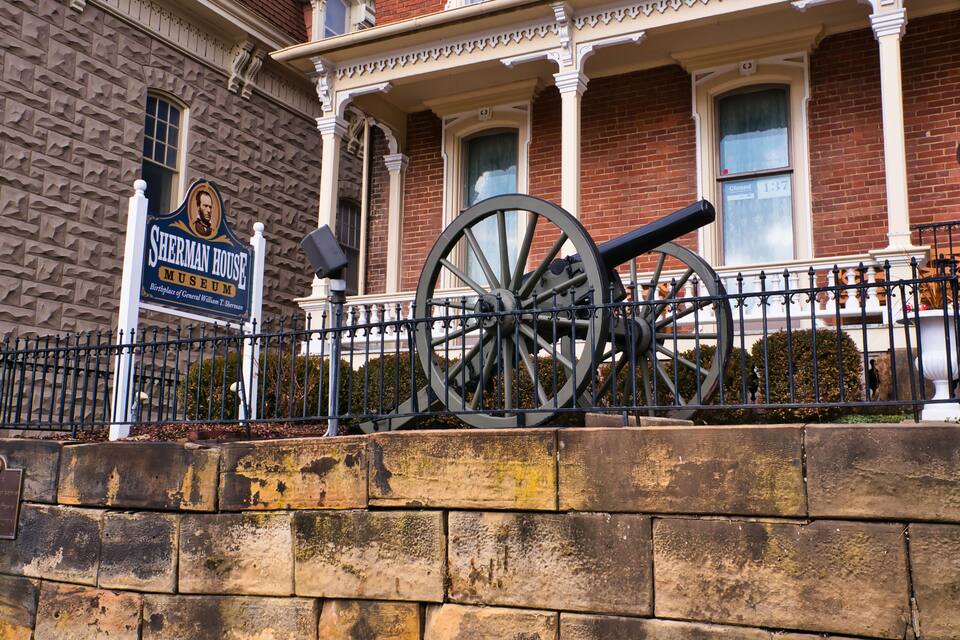 A Sherman House Museum with a large cannon in front.