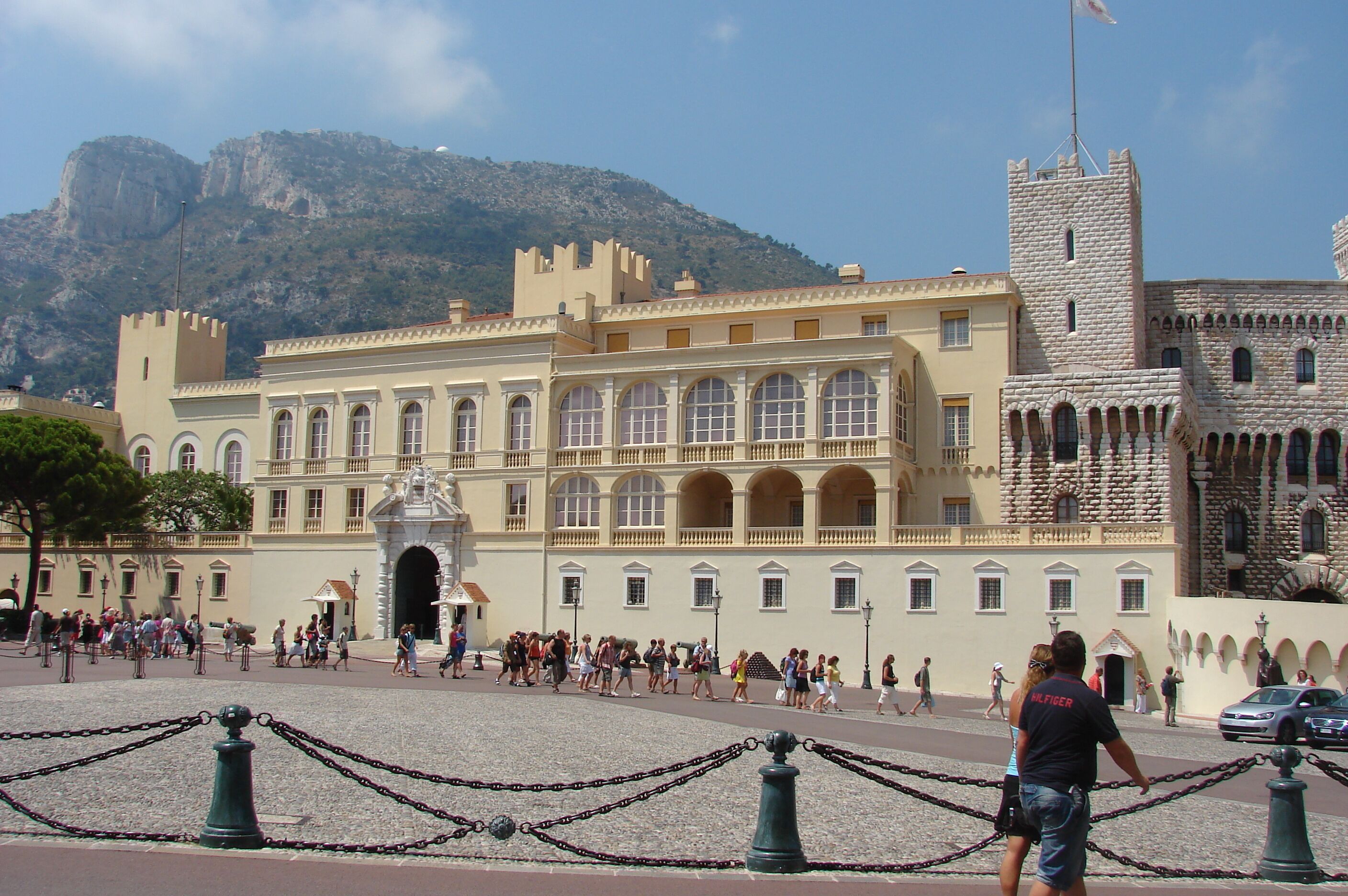 A historic building with arched windows and a tower, surrounded by a crowd of people.