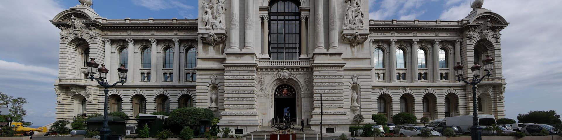 A grand neoclassical building with ornate columns and statues, featuring a large central entrance and a clock tower.