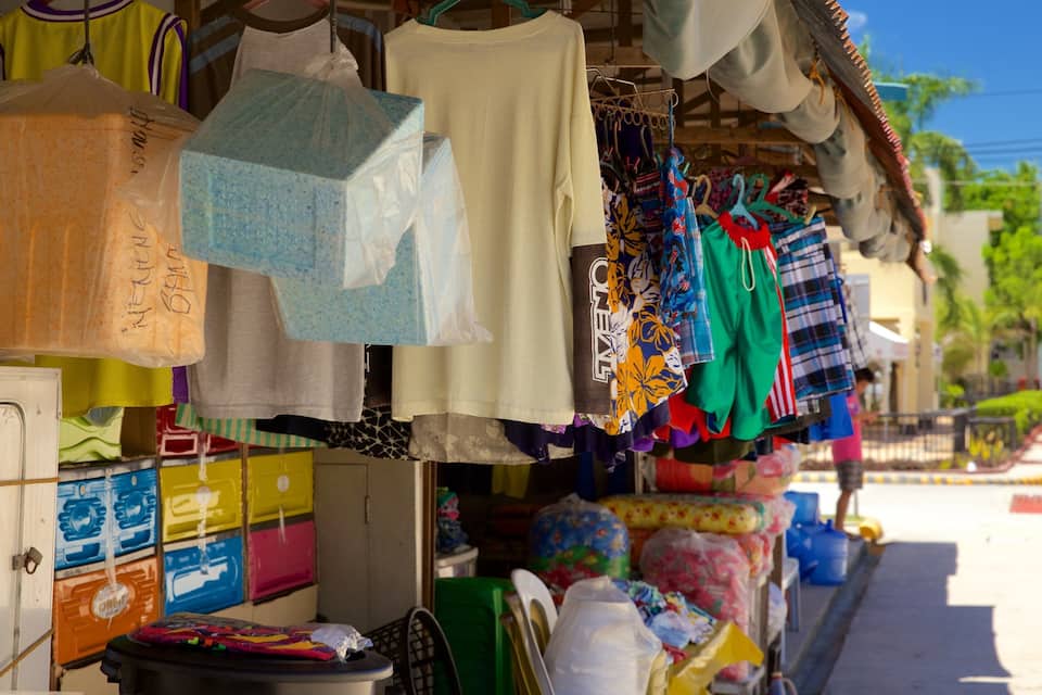 Ein Straßenmarkt mit bunten Textilien und Taschen, die auf Regalen präsentiert werden.