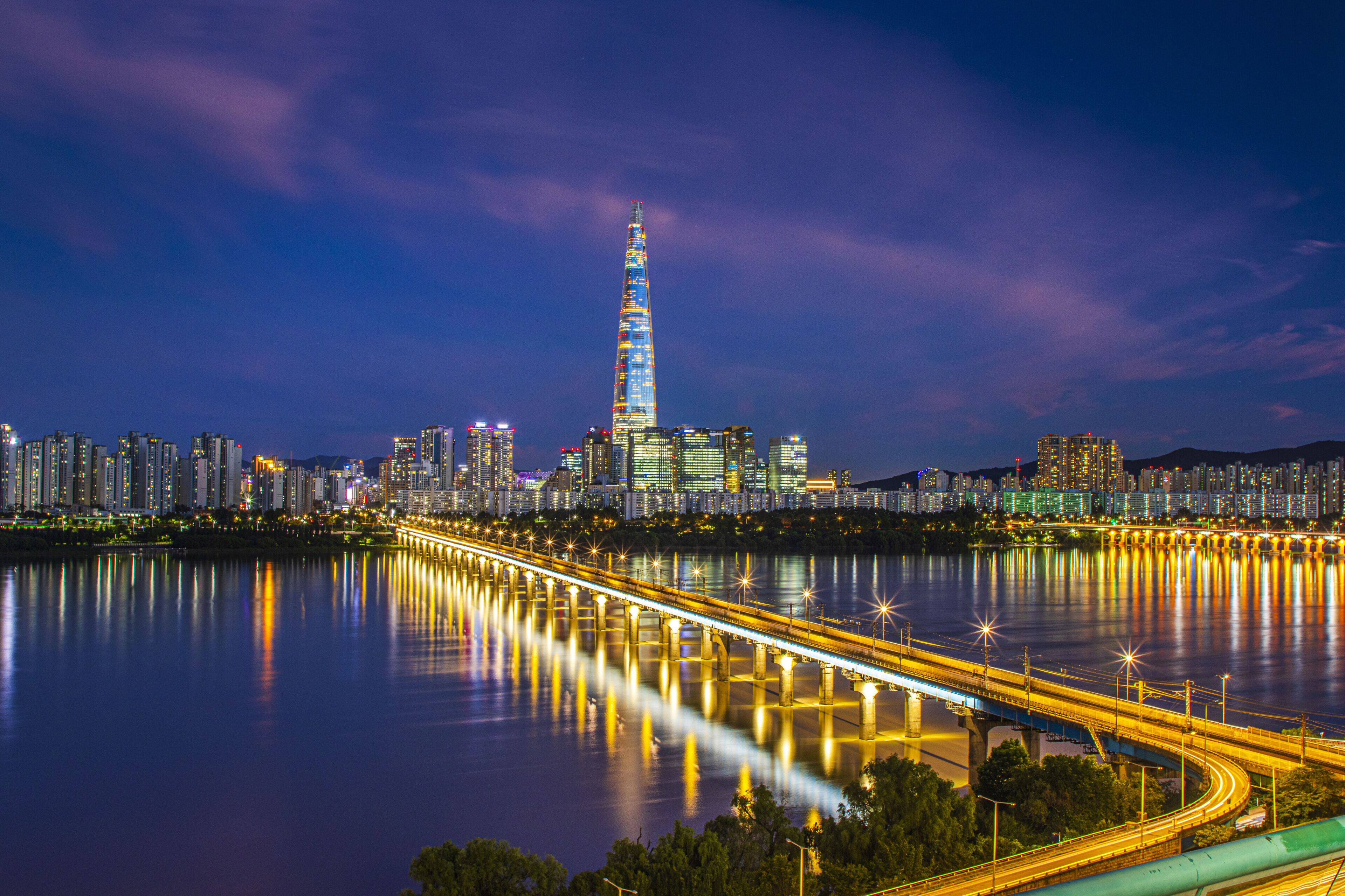 Gwangjin-gu, Seoul, South Korea - July 18, 2023: Night view of Jamsil Railroad Bridge on Han River against Lotte World Tower and apartments

