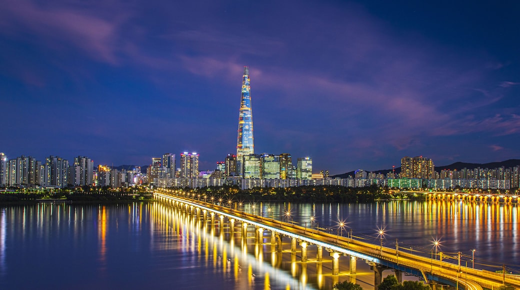 Gwangjin-gu, Seoul, South Korea - July 18, 2023: Night view of Jamsil Railroad Bridge on Han River against Lotte World Tower and apartments
