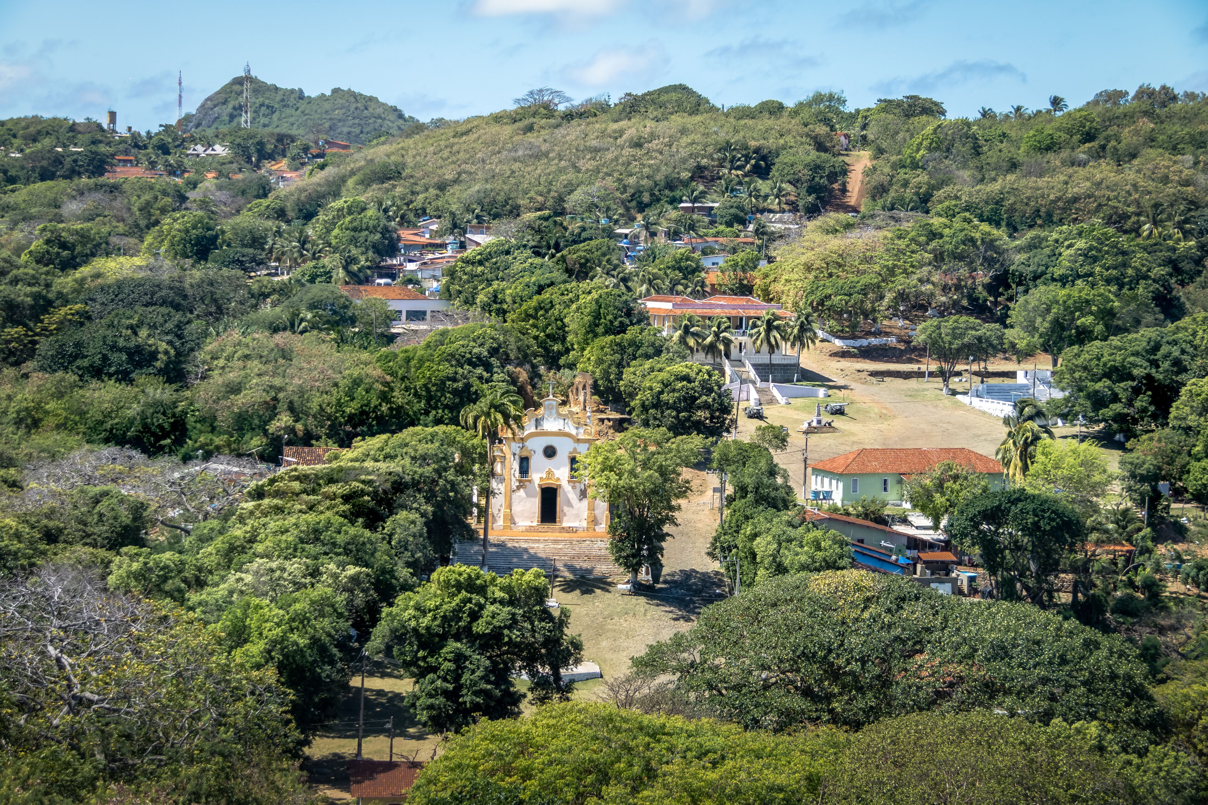 A hillside village with a prominent church, lush greenery, and scattered houses.