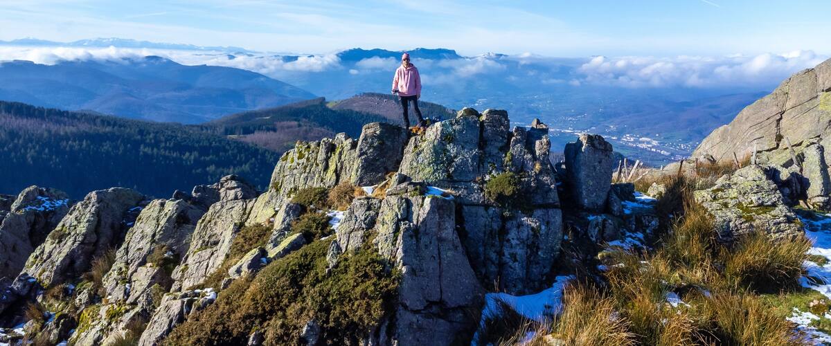 A person standing on rocky terrain with a mountainous landscape in the background.