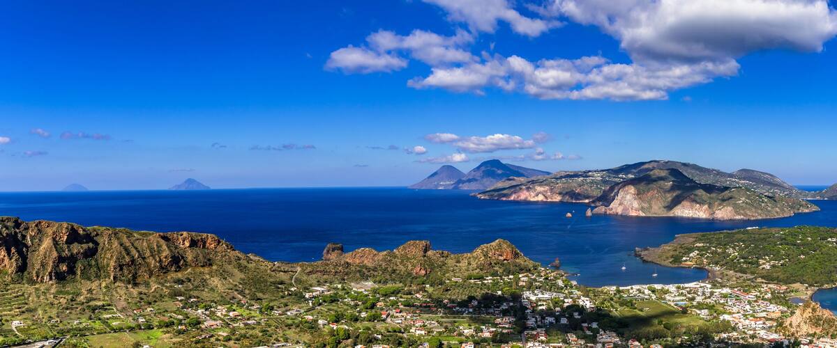 A coastal town with a harbor, mountains, and a clear blue sky.