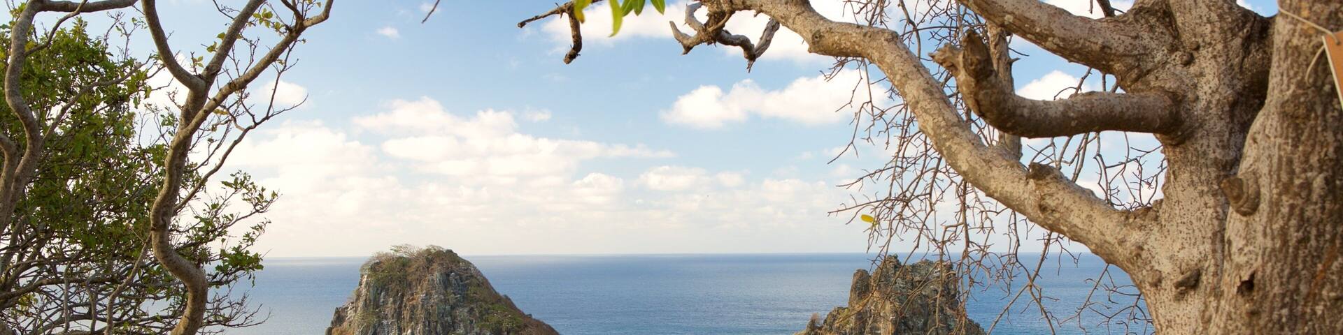 A coastal landscape with two prominent rock formations surrounded by turquoise waters.