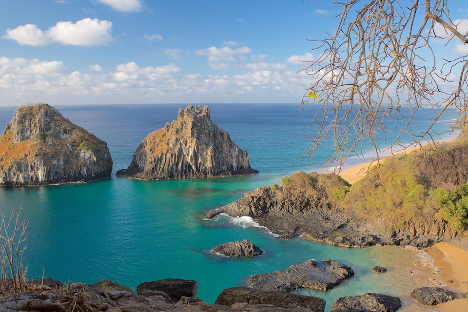 A coastal landscape with two prominent rock formations surrounded by turquoise waters.