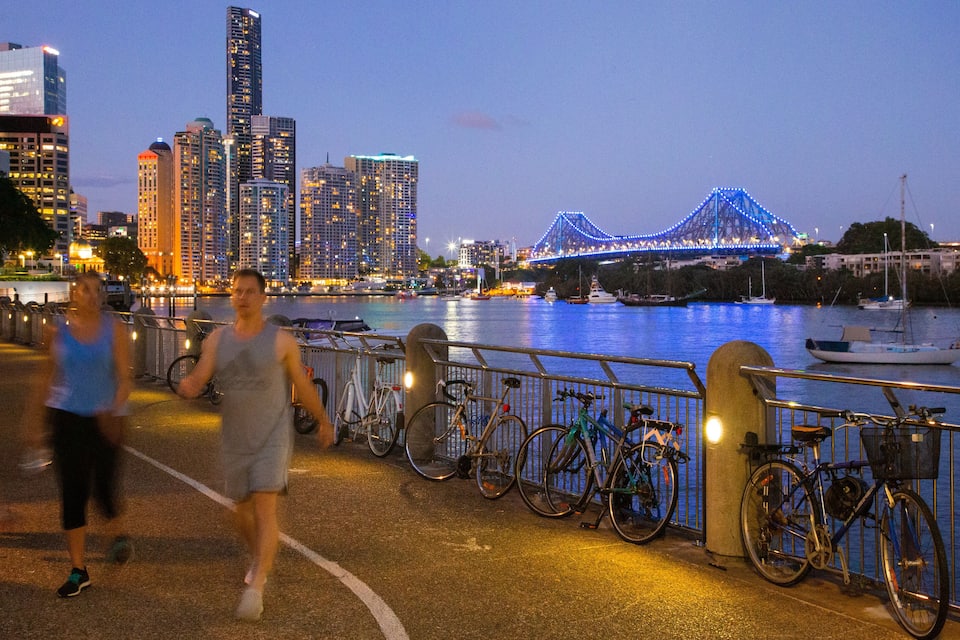 Un paisaje urbano al atardecer con un puente iluminado y rascacielos.