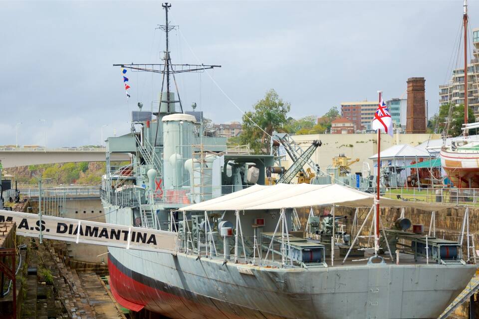 A large ship named A.S. Diamantina docked at a port with industrial structures and buildings in the background.