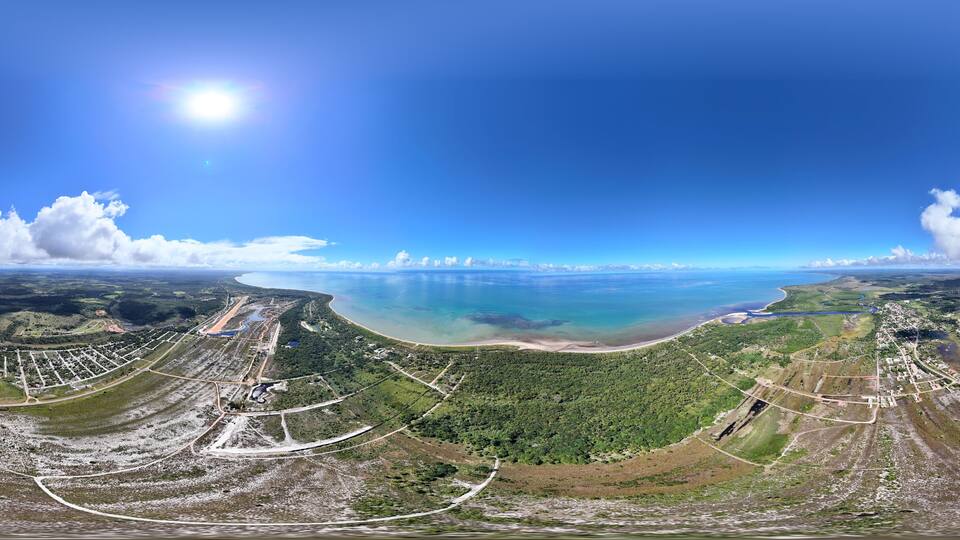 An aerial view of a coastal landscape with a large body of water, a beach, and surrounding greenery.