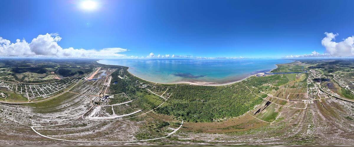 An aerial view of a coastal landscape with a large body of water, a beach, and surrounding greenery.