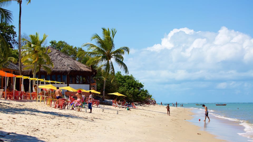 A beach with palm trees, a thatched-roof hut, and people relaxing under umbrellas.