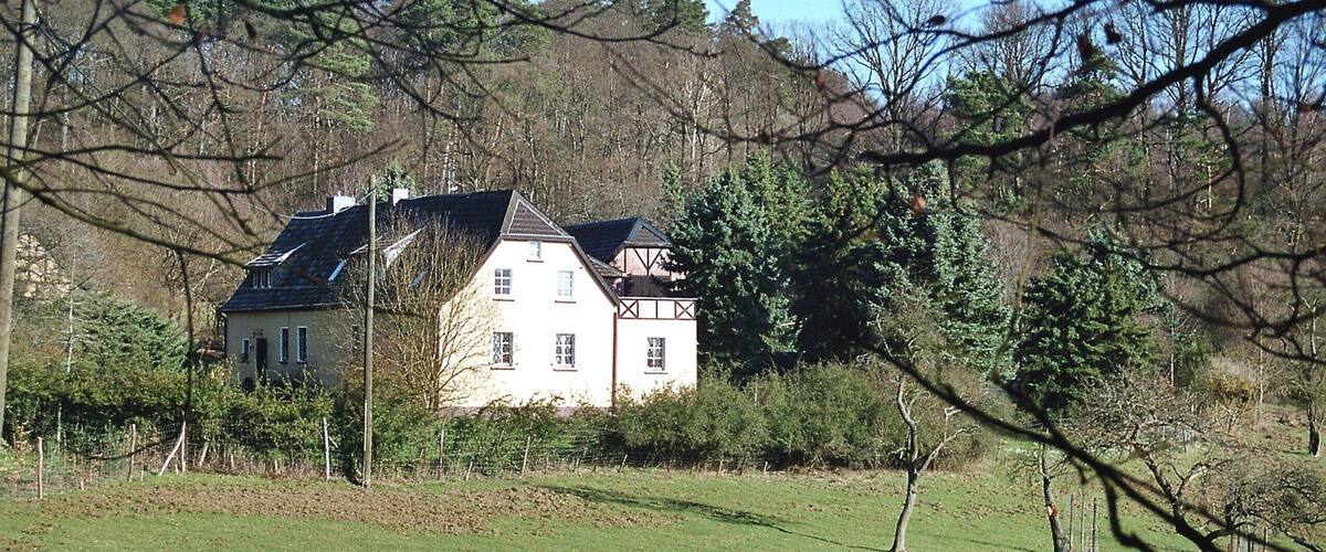 A large house surrounded by a green field and trees.