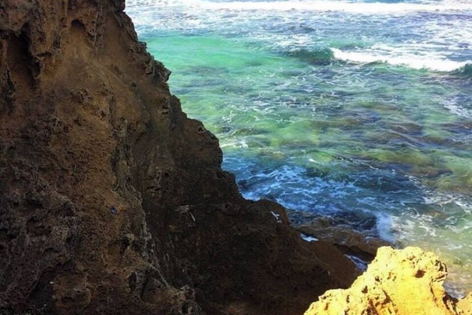 Um litoral rochoso com águas azuis cristalinas e um penhasco.