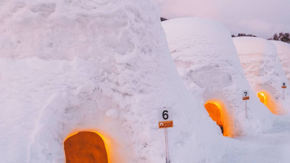 Igloos with numbered signs, a snowy landscape, and a sunset.