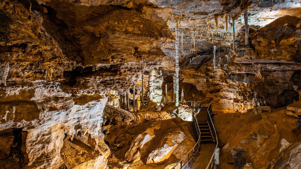 A cave with stalactites, a staircase, and a rocky floor.