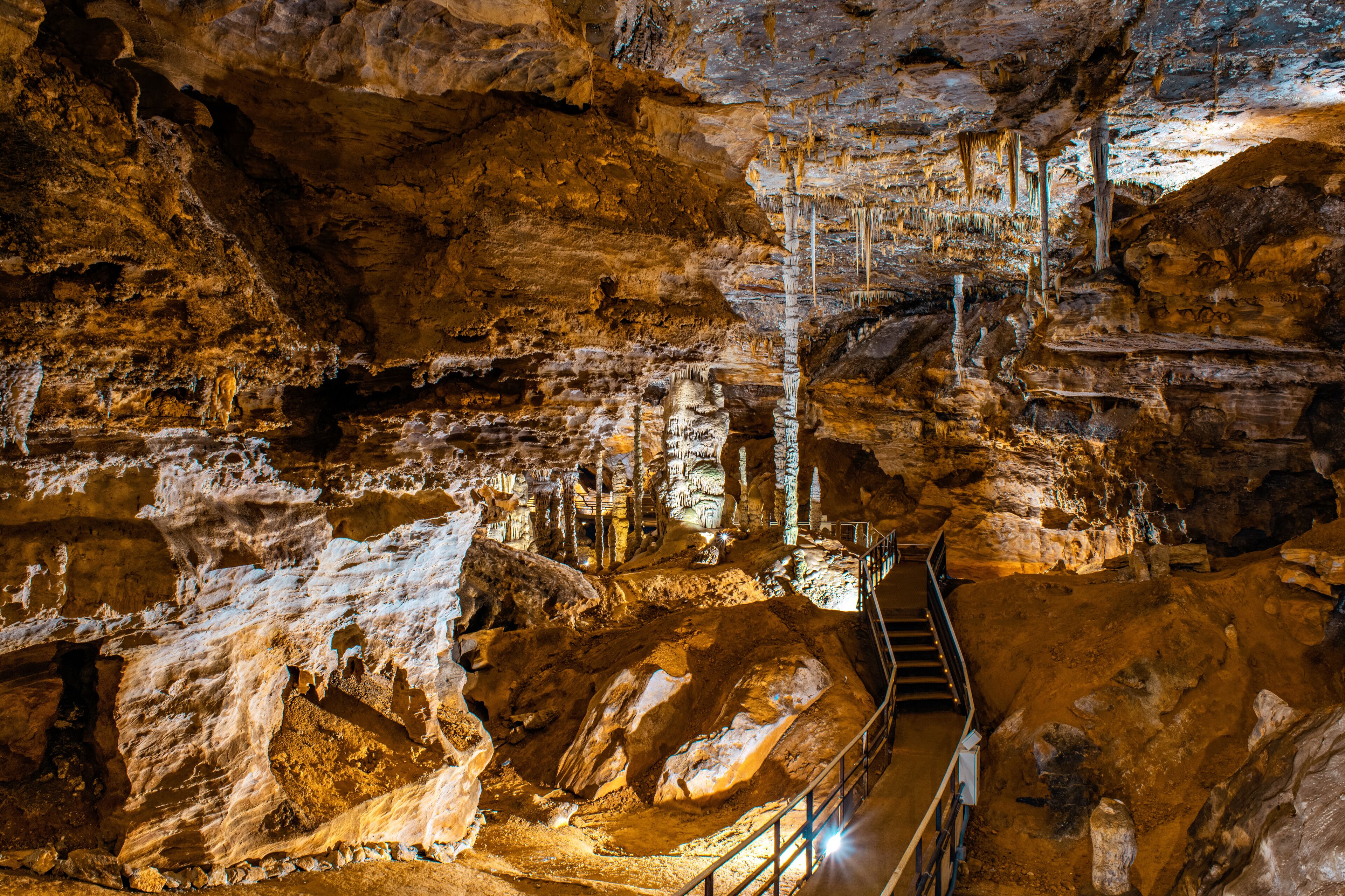 A cave with stalactites, a staircase, and a rocky floor.