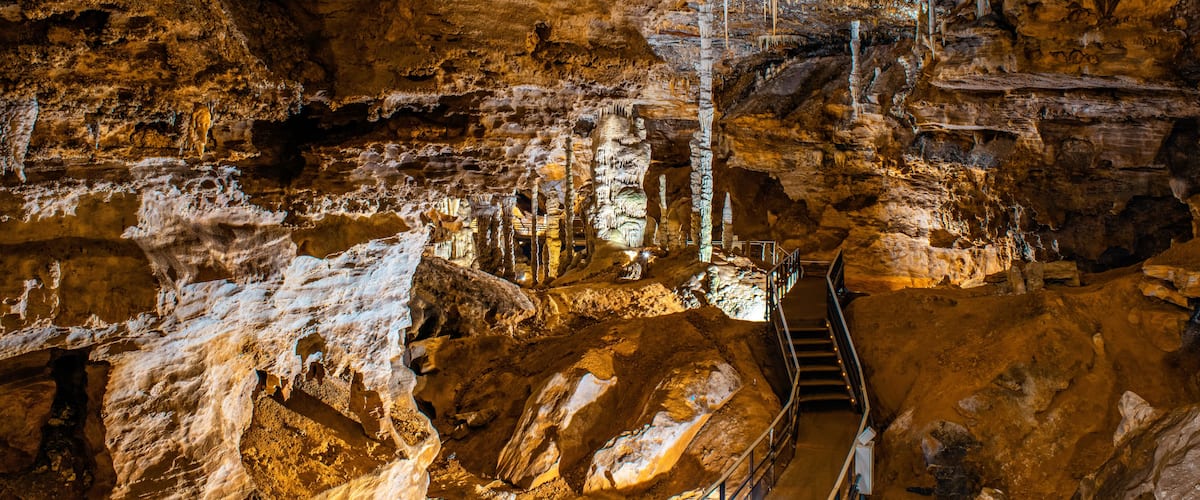 A cave with stalactites, a staircase, and a rocky floor.