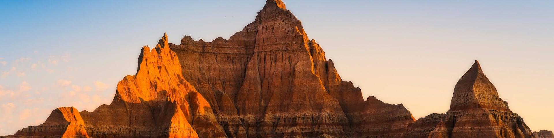 A rugged landscape with prominent buttes and a grassy field.