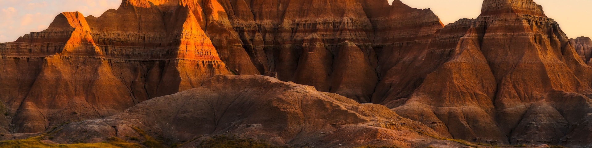 Un paisaje agreste con buttes destacados y un campo cubierto de hierba.