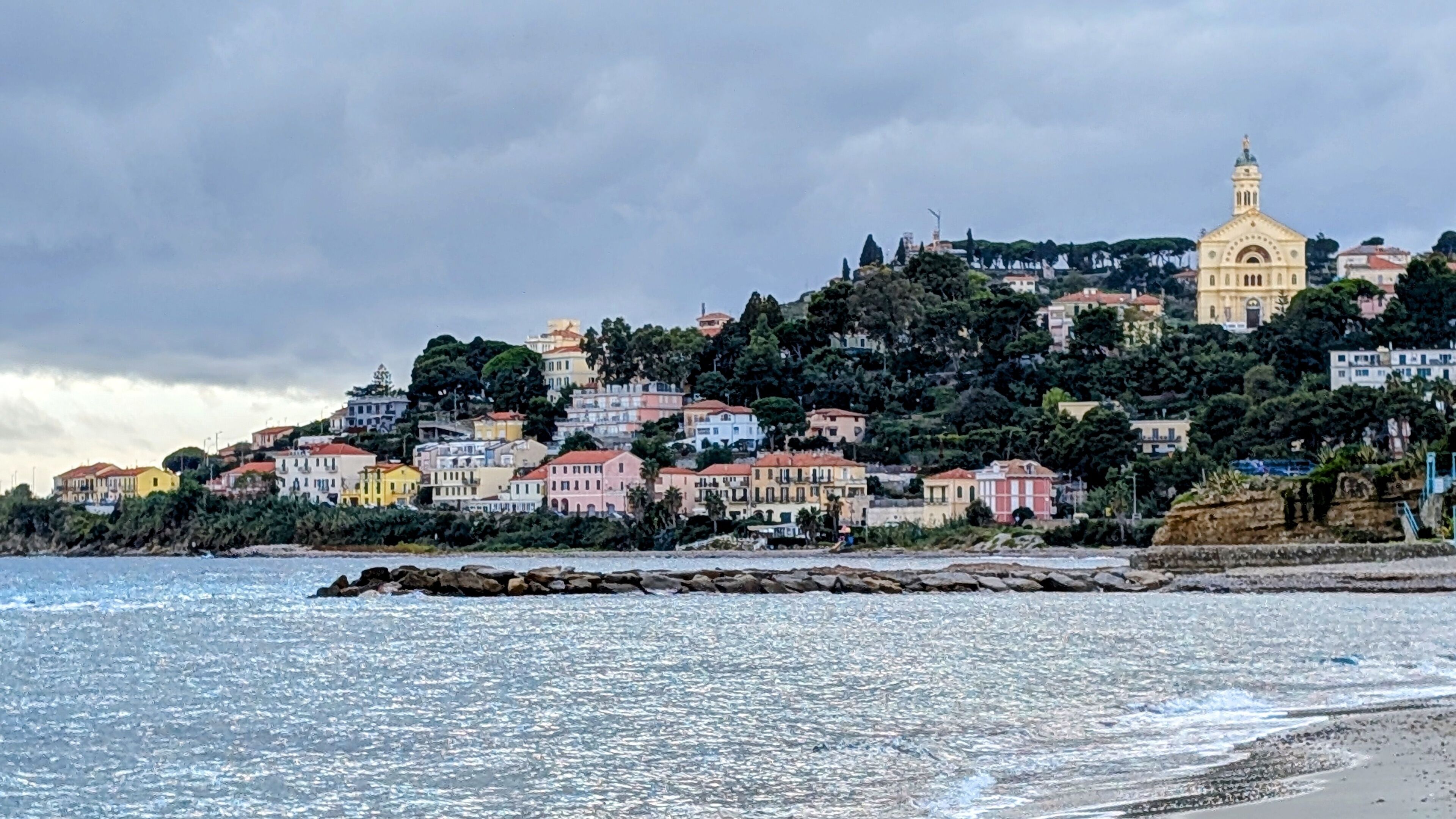 A coastal town with colorful buildings, a prominent church, and a rocky shoreline.