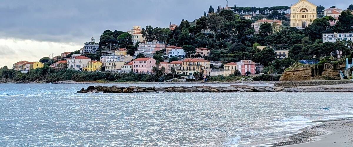 A coastal town with colorful buildings, a prominent church, and a rocky shoreline.