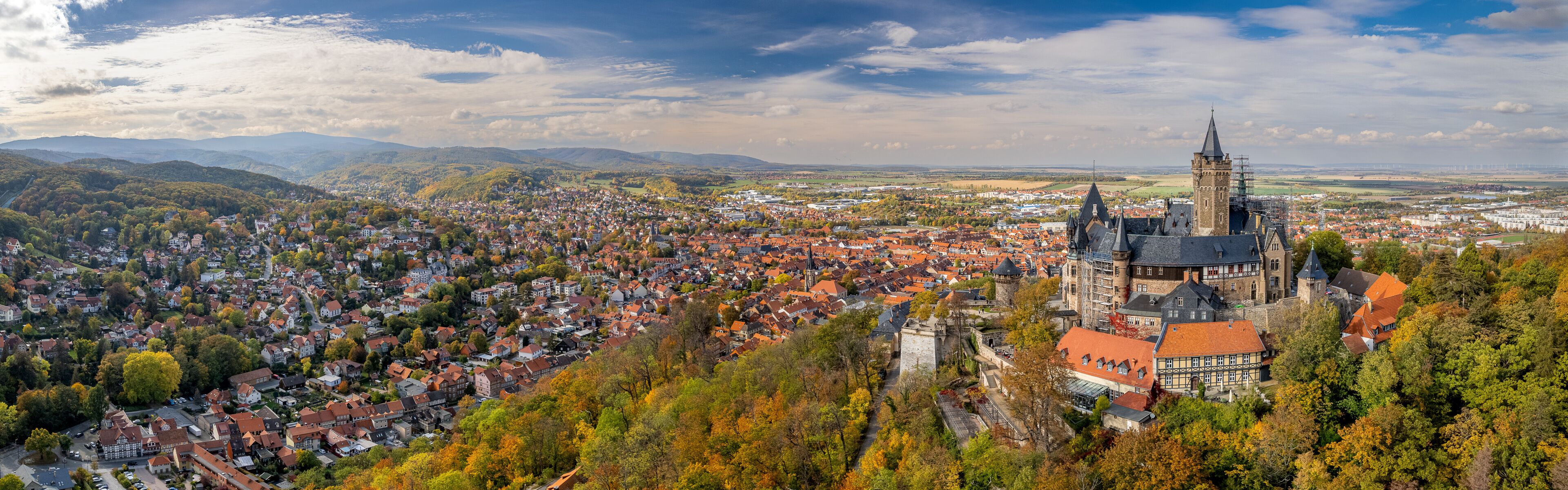 Een panoramisch uitzicht op een stad met een opvallende toren en omliggende heuvels.