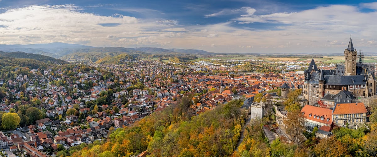 Ein weitreichender Blick auf eine Stadt mit einem markanten Turm und sanften Hügeln.