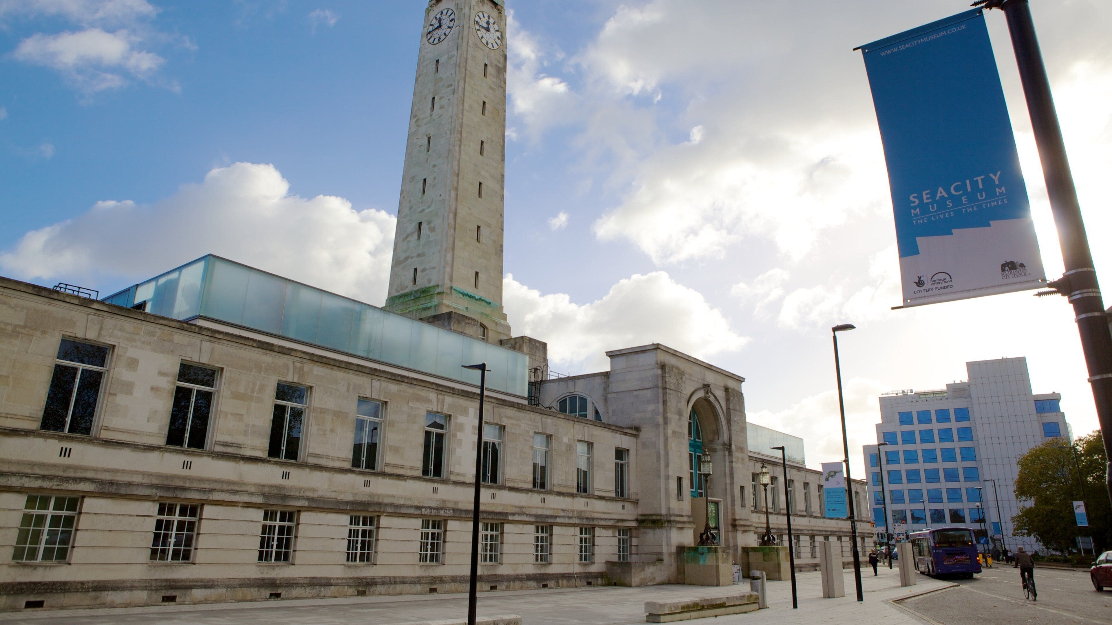 A historic building with a clock tower, a modern glass extension, and a banner for the Seacity Museum.