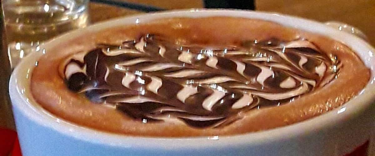 A cup of coffee with latte art on a red napkin.