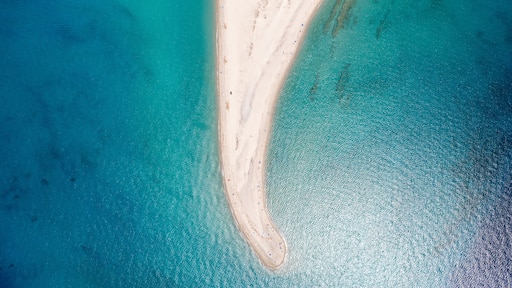 Stunning aerial perspective of a sandy beach extending into vibrant turquoise waters in Kassandra, Halkidiki, Greece, showcasing natural beauty