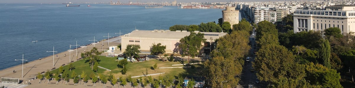 Un paysage urbain côtier avec un château imposant, un port de plaisance et un mélange de bâtiments modernes et historiques.
