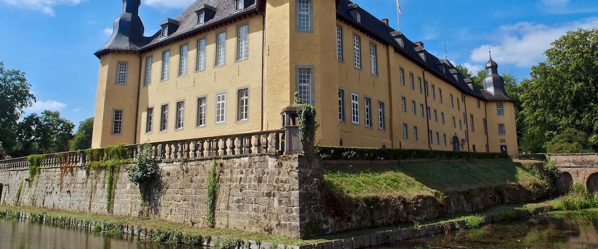 Un grand bâtiment jaune, doté de deux coupoles et entouré de douves.