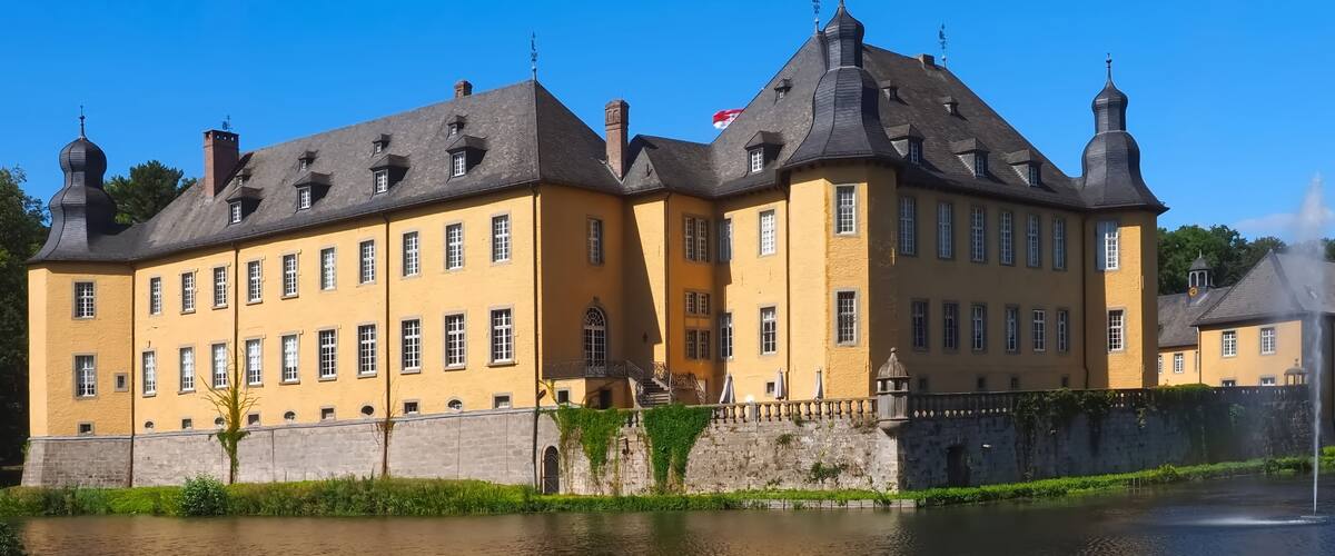 A historic yellow building with multiple towers and a moat.