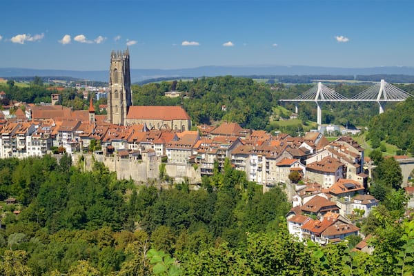 A historic town with a prominent church, a bridge, and lush greenery.