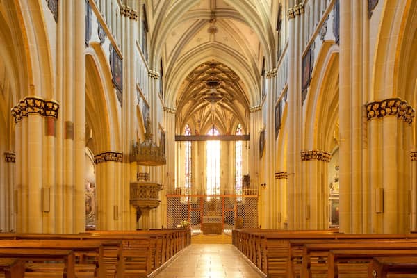 Ein gotischer Dom mit hohen Gewölbedecken, schlanken Säulen und farbenprächtigen Glasfenstern.